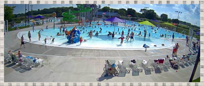 an aerial view of a large swimming pool with people playing in the water and onlookers watching