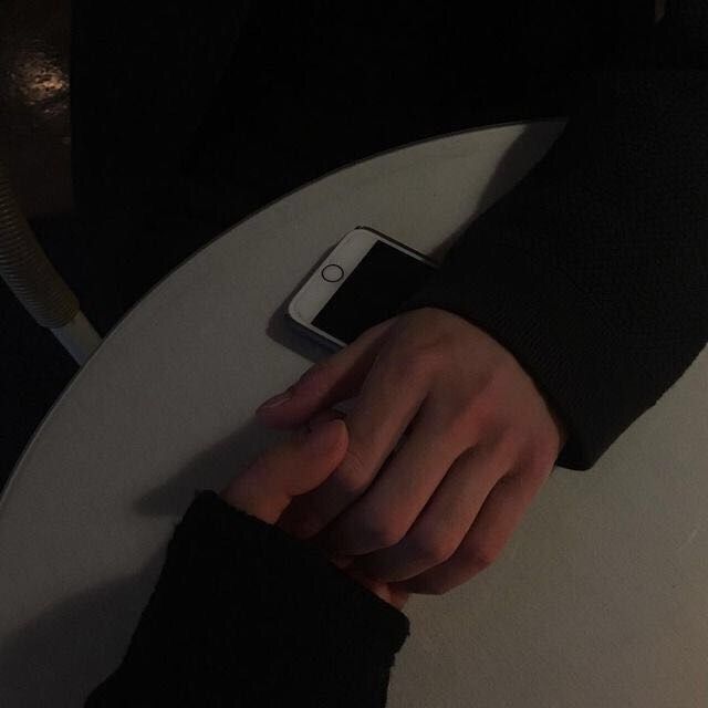 a person's hand on top of a table with a cell phone in it