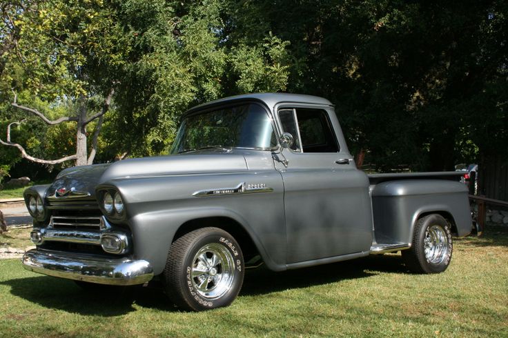 an old gray truck parked in the grass