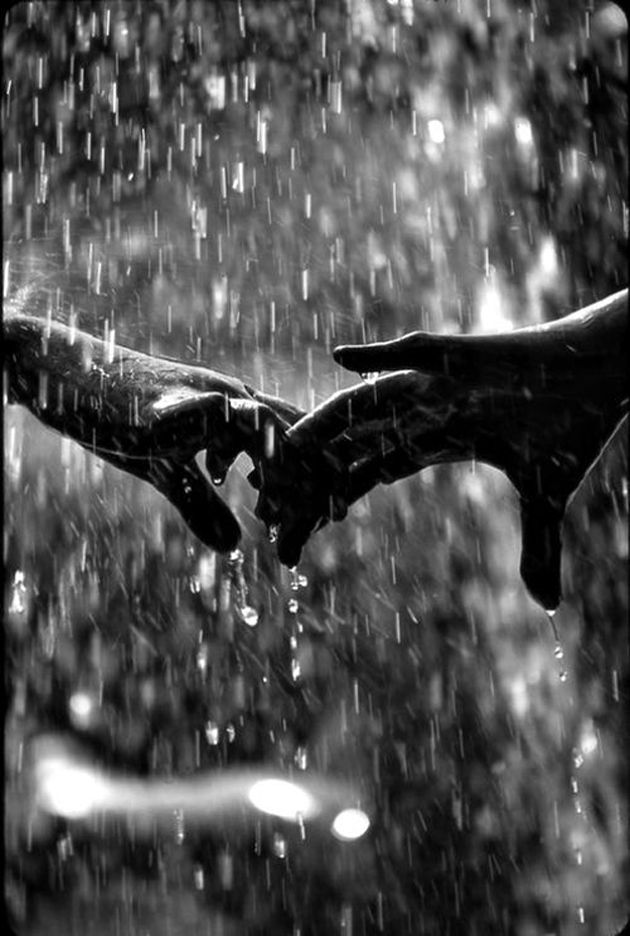 two hands holding each other in the rain