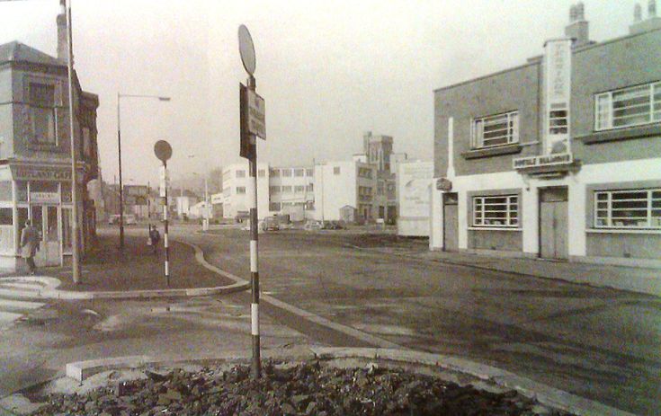 an old black and white photo of a street corner with buildings on both sides in the background