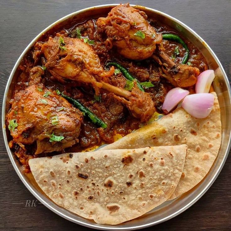 a plate filled with meat and tortillas on top of a wooden table