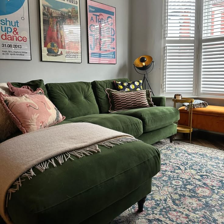 a living room with green couches and pictures on the wall