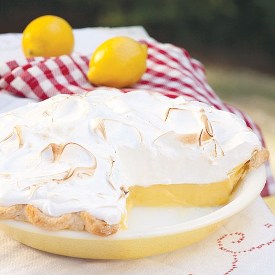 a lemon pie sitting on top of a white plate next to a red and white checkered napkin