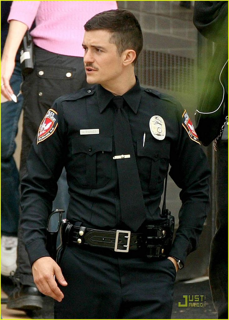 a police officer is standing in front of some people wearing sunglasses and holding his hand on his hip