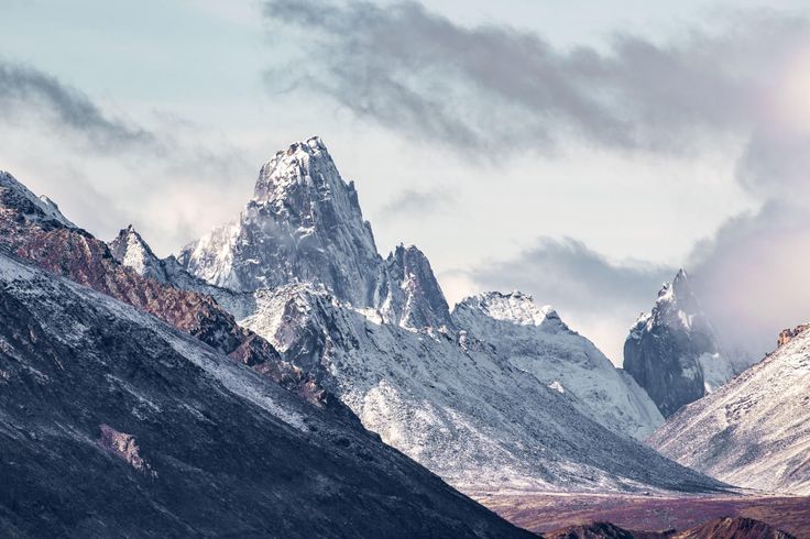 the mountains are covered in snow and clouds