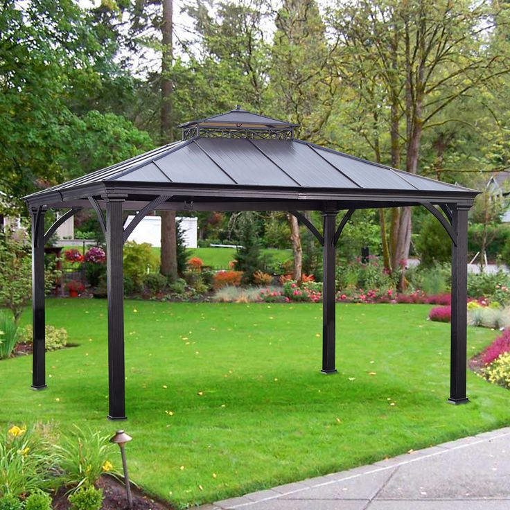 a gazebo sitting in the middle of a lush green park with lots of flowers