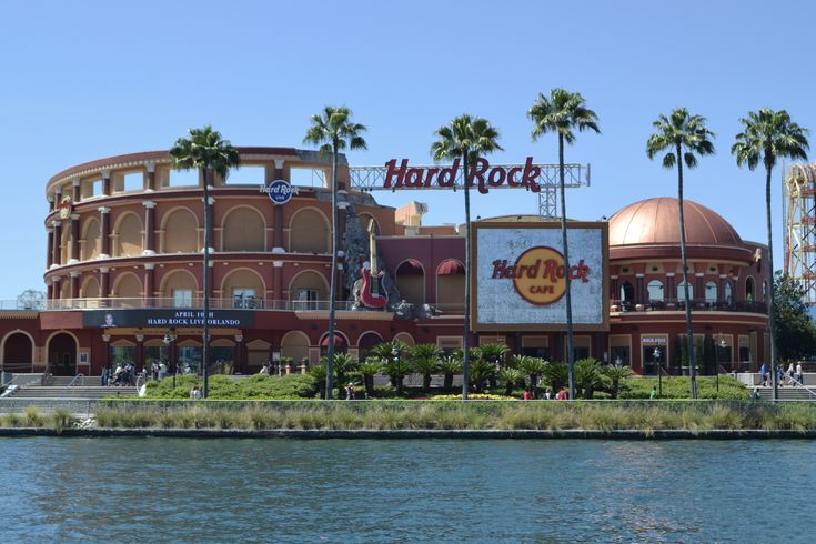 the hard rock casino is next to some water and palm trees in front of it