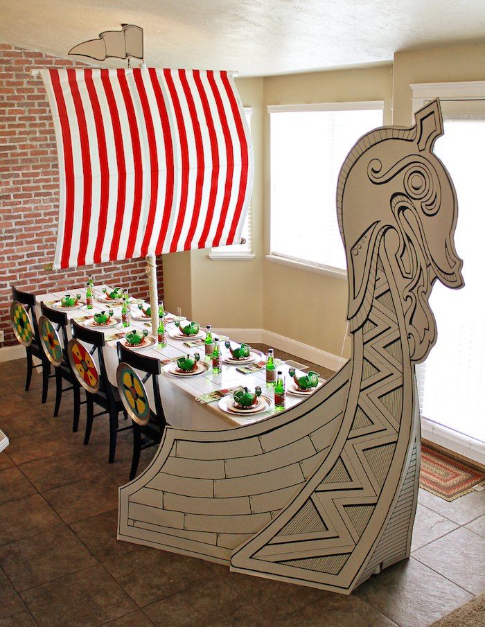 a long table with plates and cups on it in front of a boat shaped like a ship