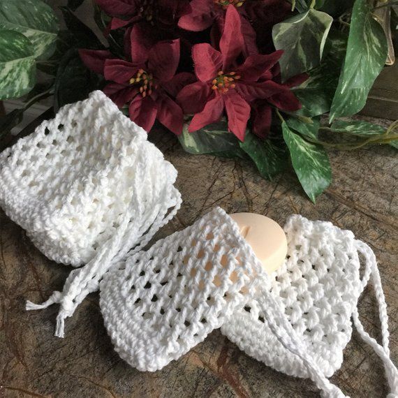 two white crocheted bags sitting on top of a wooden table next to flowers