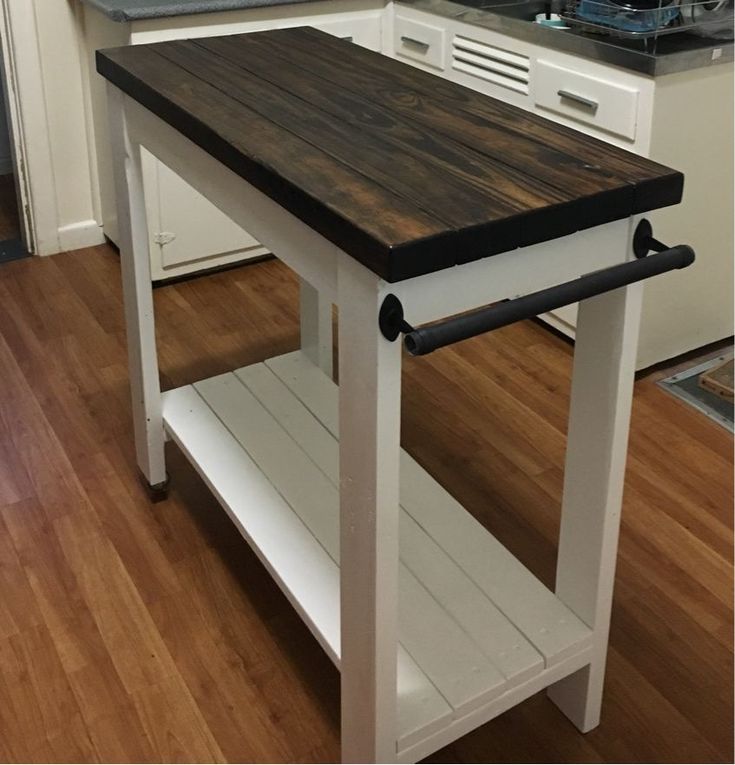 a kitchen island made out of wood and white painted cabinets with black accents on the top