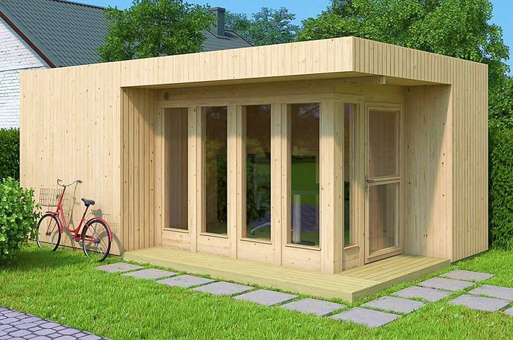 a small wooden building sitting on top of a lush green field next to a bike