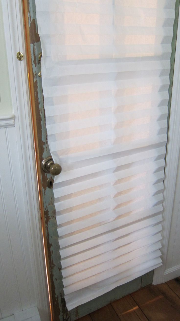 an open door with white blinds on the side and wood flooring in front of it