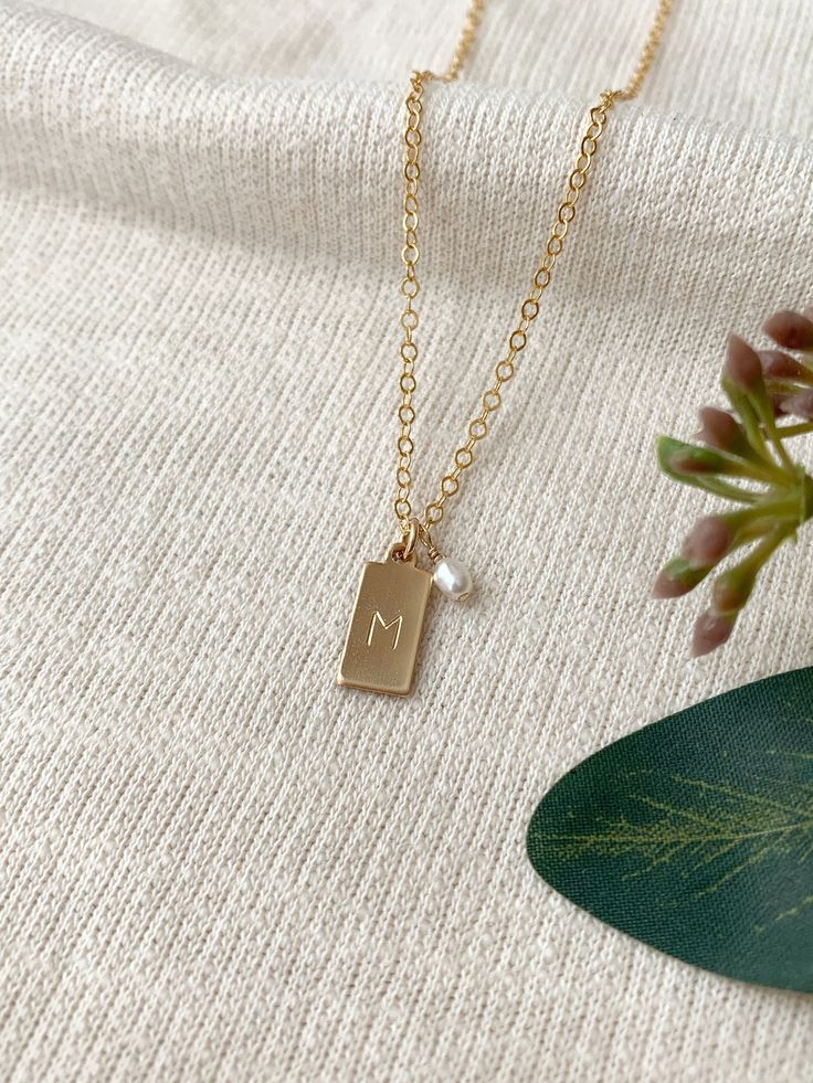 dainty initial necklace, gift for mom, dainty gold necklace, letter necklace, gift for her, stocking stuffer, holiday gift for her, jewelry gift for her Details: This necklace can be personalized for yourself or to give as a thoughtful gift! Each adorable tiny rectangle charm is hand stamped with the initial of your choice. This makes a gorgeous simple and meaningful every day necklace. * Tiny 14K Gold Filled or 925 Sterling Silver 13x6mm rectangle tag charm * Freshwater pearl charm (removable u Dainty Initial Necklace, Custom Initial Necklace, Dainty Gold Necklace, Monogram Necklace, Keepsake Jewelry, Vermeil Jewelry, Personalized Gifts For Her, Pearl Charms, Letter Necklace