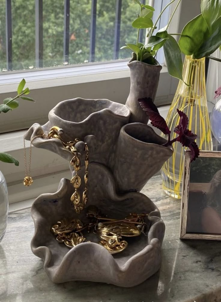 two vases with plants in them on a table next to a window sill