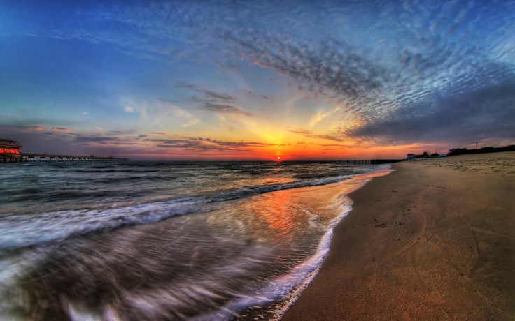 the sun is setting at the beach with waves coming in