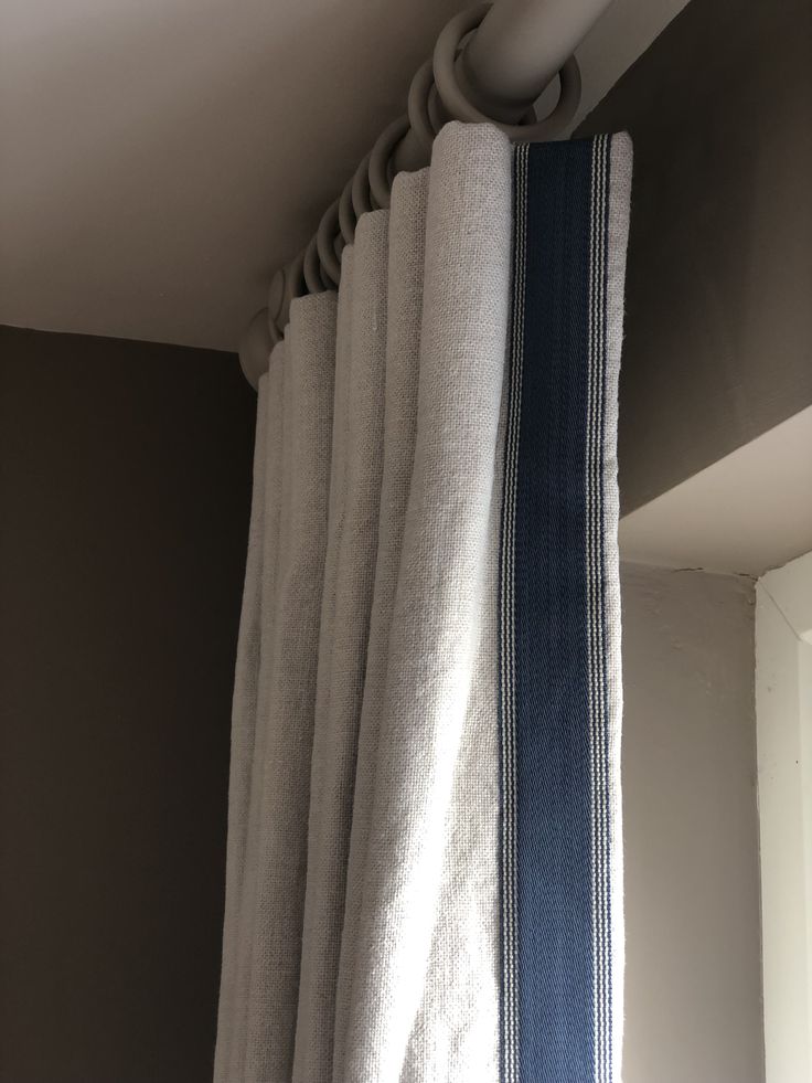 an open curtain with blue and white stripes hanging from it's rodulage