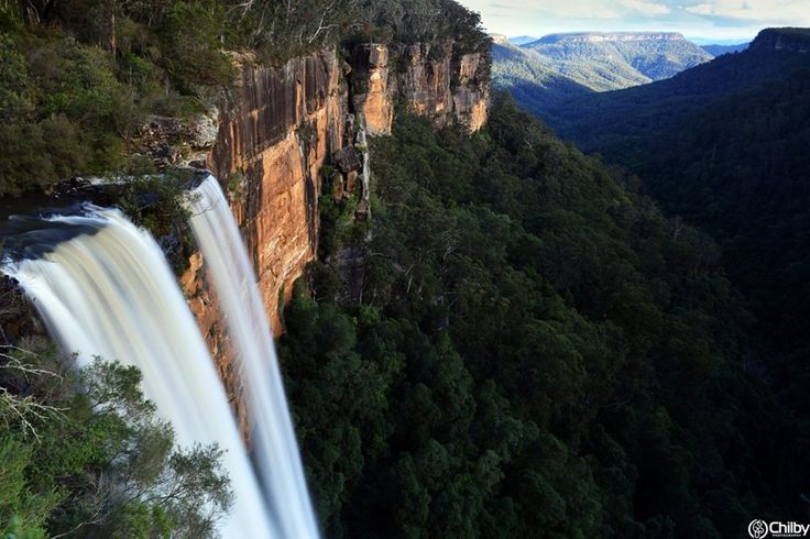 a large waterfall in the middle of a forest