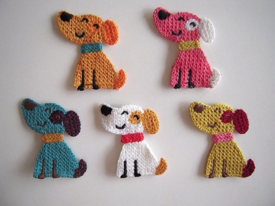 four crocheted dogs sitting next to each other on a white surface with one dog wearing a red collar