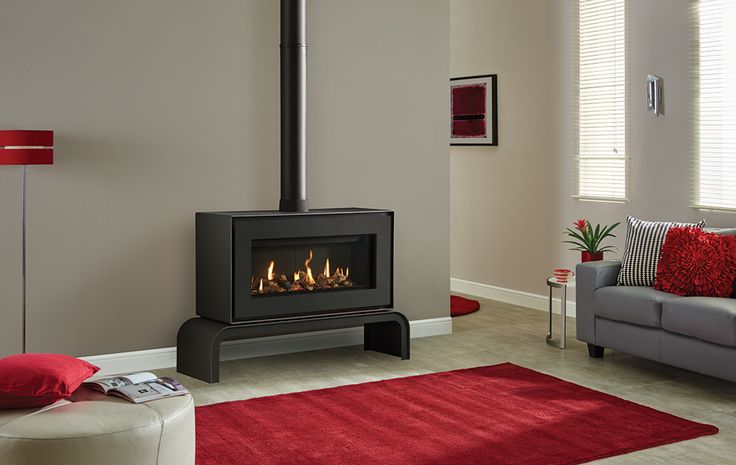 a living room with a fire place in the center and red rugs on the floor