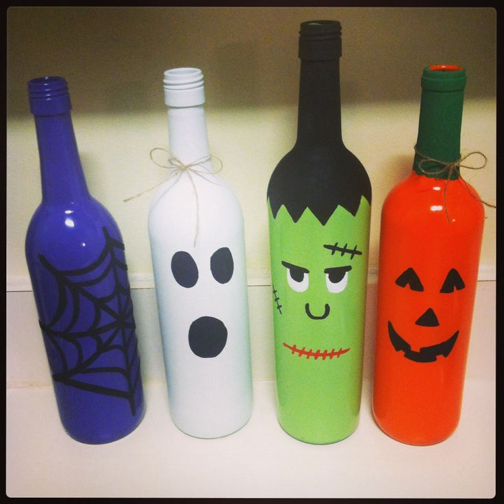 four halloween wine bottles are lined up in a row with faces painted on the bottles