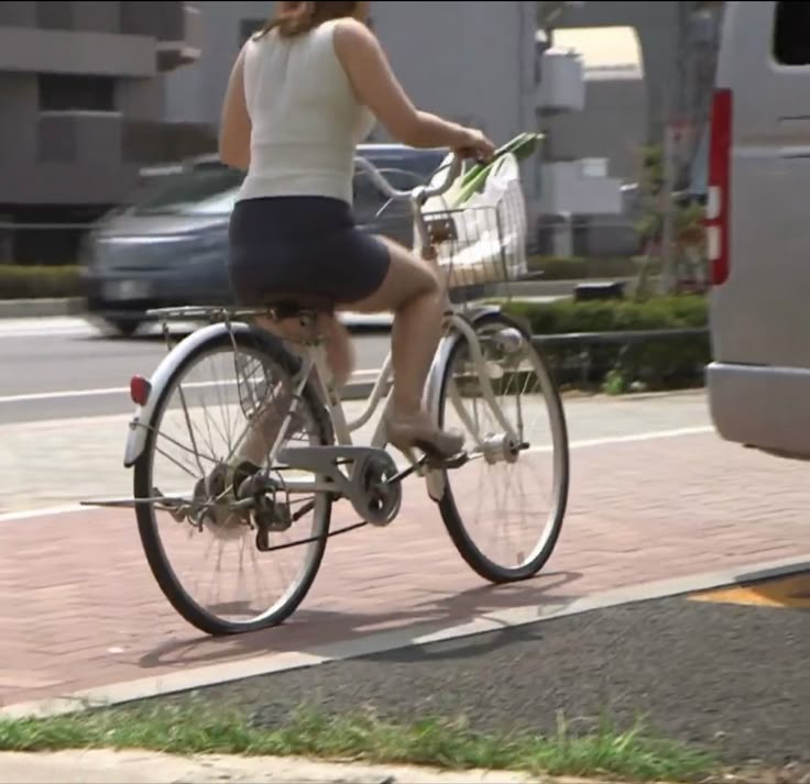 the woman is riding her bike down the street