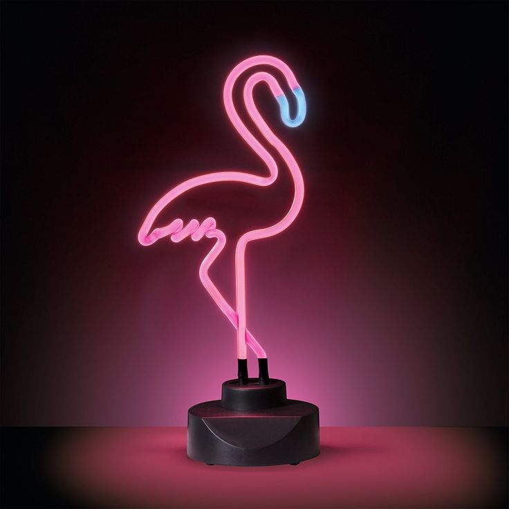 a pink flamingo neon sign sitting on top of a black stand in the dark