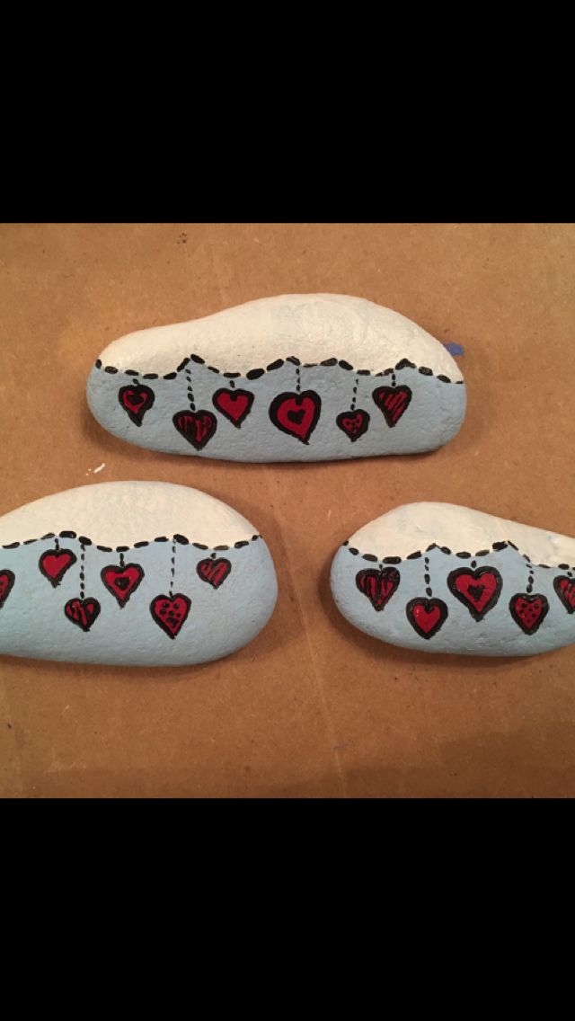 three rocks with hearts on them are sitting on a table and one is painted white