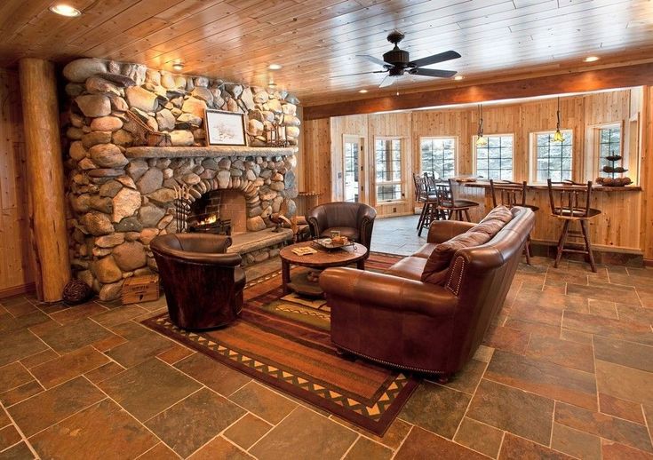 a living room filled with furniture next to a stone fire place and a ceiling fan