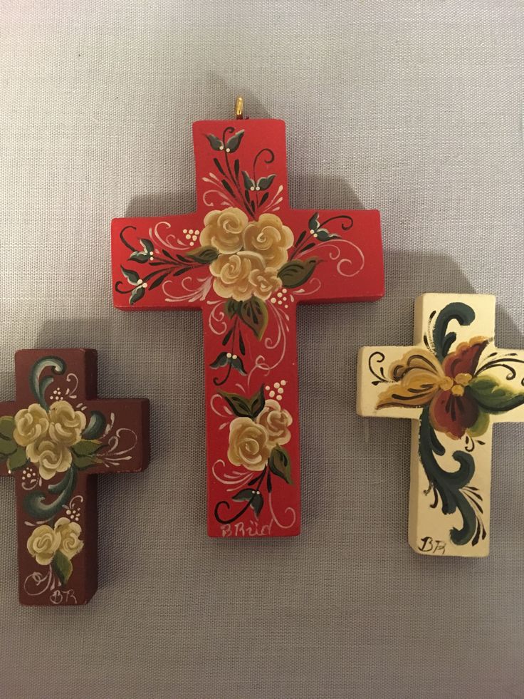 three wooden crosses with flowers painted on them, one is red and the other is white