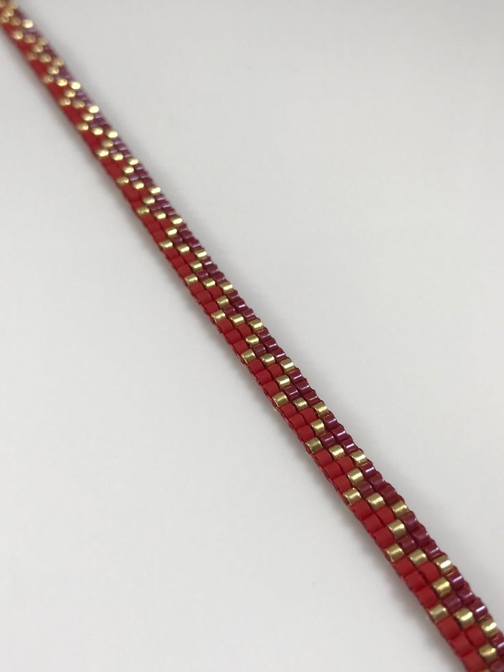 a red and gold bracelet on a white surface