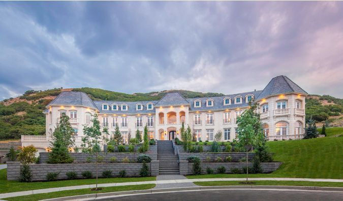 a large white mansion sitting on top of a lush green hillside