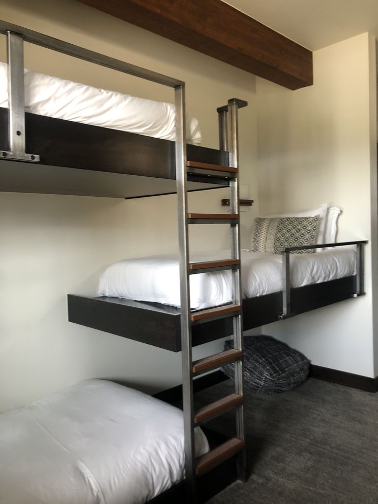 two bunk beds in a room with white sheets and pillows on the bottom bunk bed