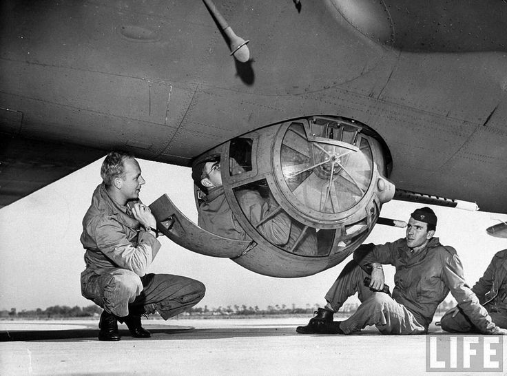 four men are working on the side of an old airplane, while another man is kneeling down next to it