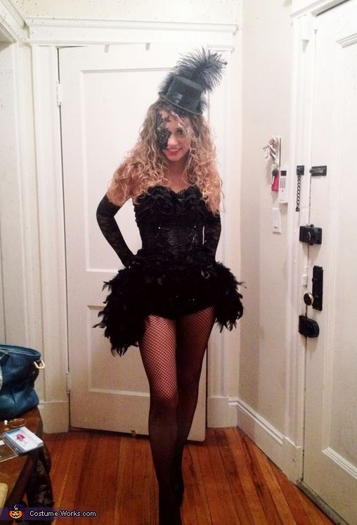 a woman in a black dress and feathered hat is standing in front of a door