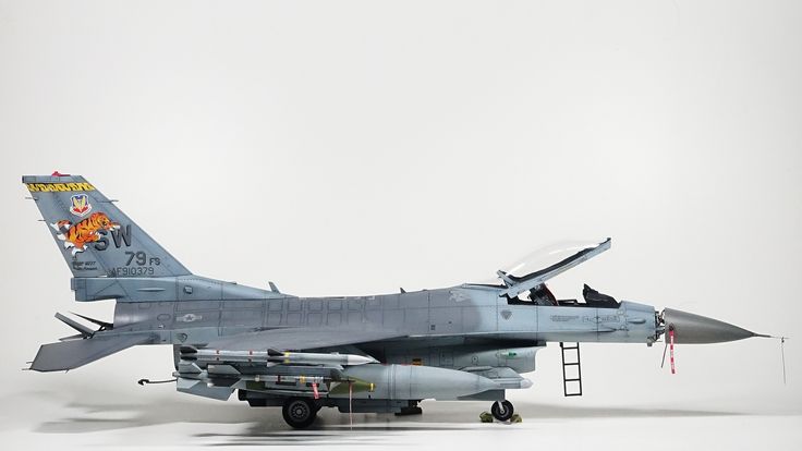 a fighter jet sitting on top of an airport tarmac next to a truck with ladders