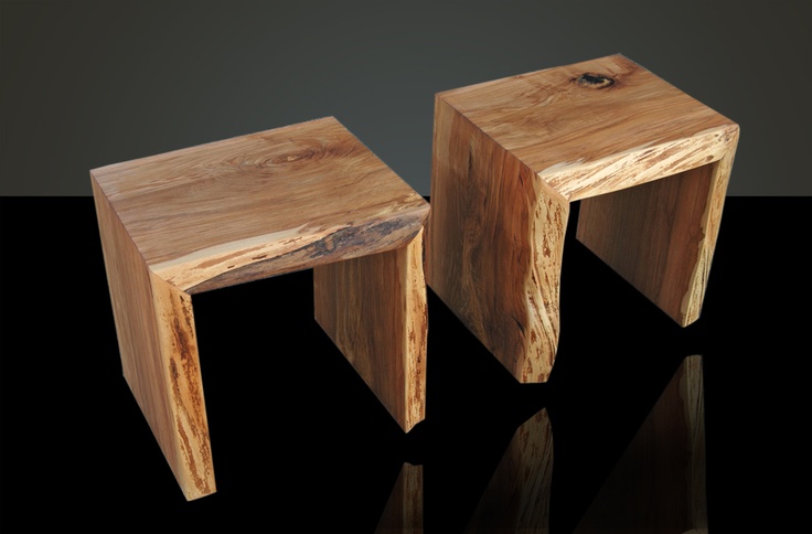 two wooden stools sitting next to each other on a black surface with reflections in the floor