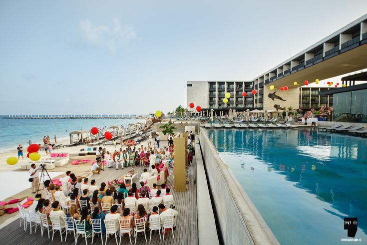 a group of people sitting at tables next to a swimming pool