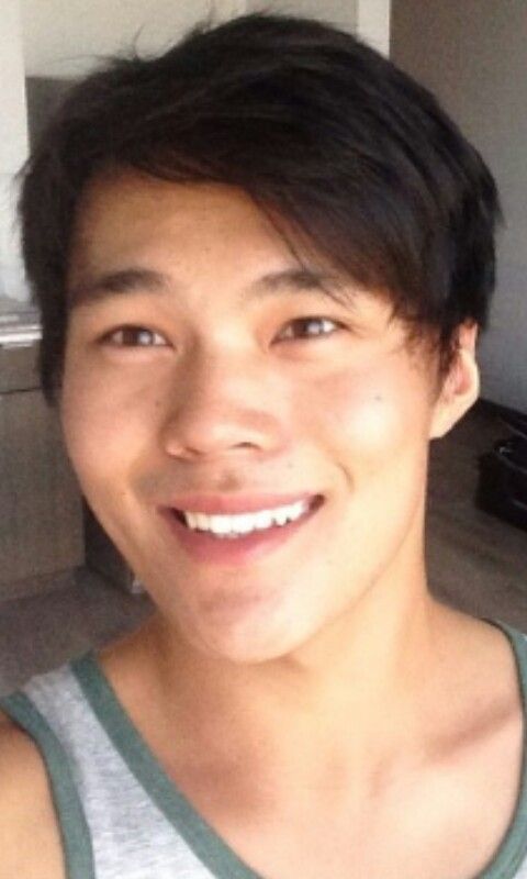 a young man smiling at the camera in a kitchen