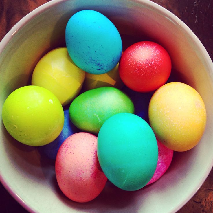 a white bowl filled with colorfully dyed eggs