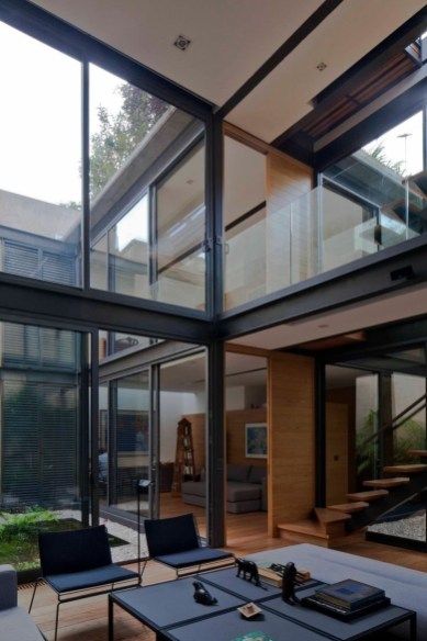 an open living room with glass walls and stairs leading up to the second floor area