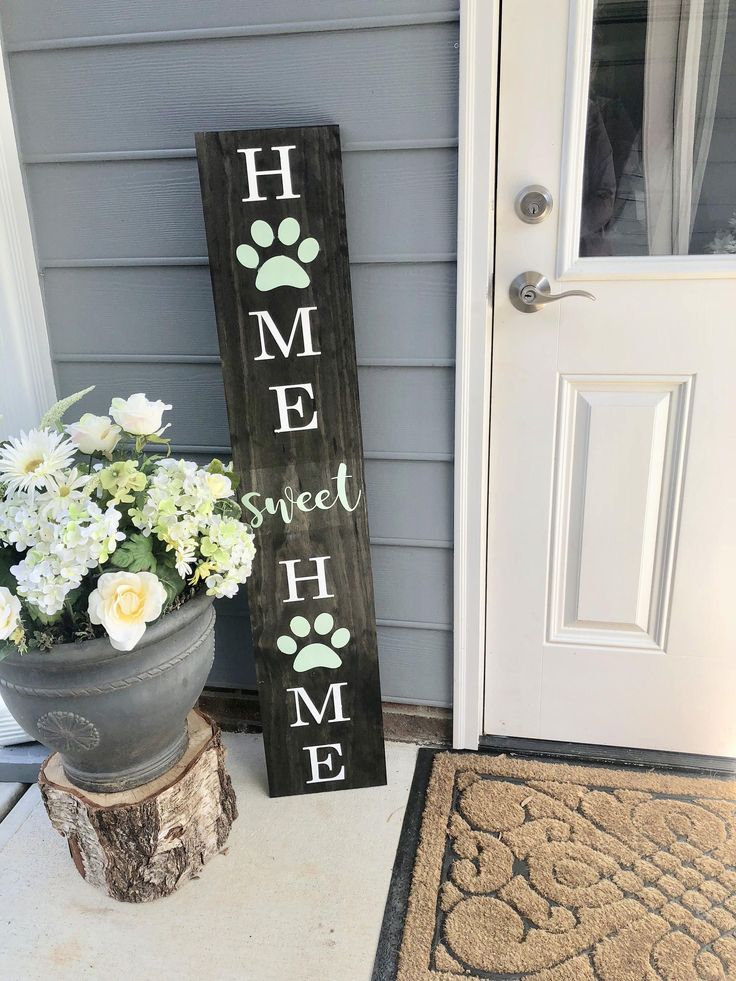 a sign that says home sweet home is next to a potted plant on the porch