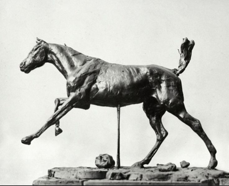 a statue of a running horse on top of a stone block in front of a sky background