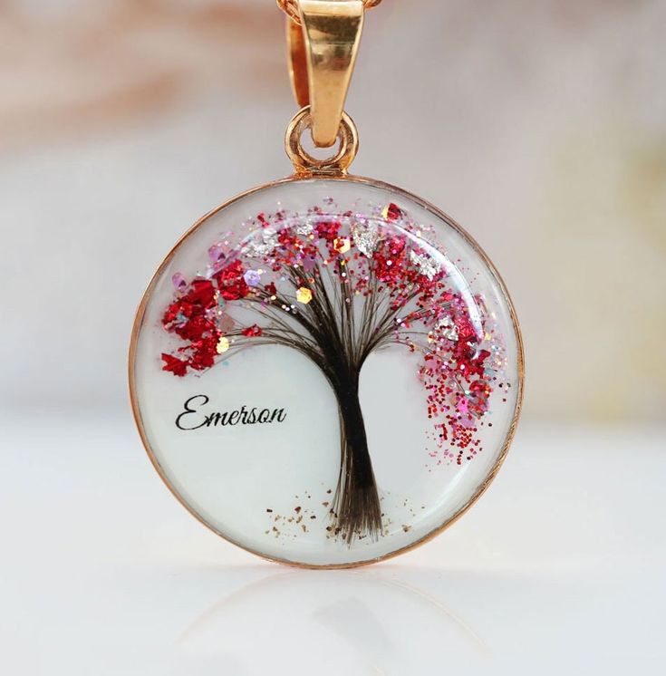 a necklace with a tree on it and the name emberson written in red glitters