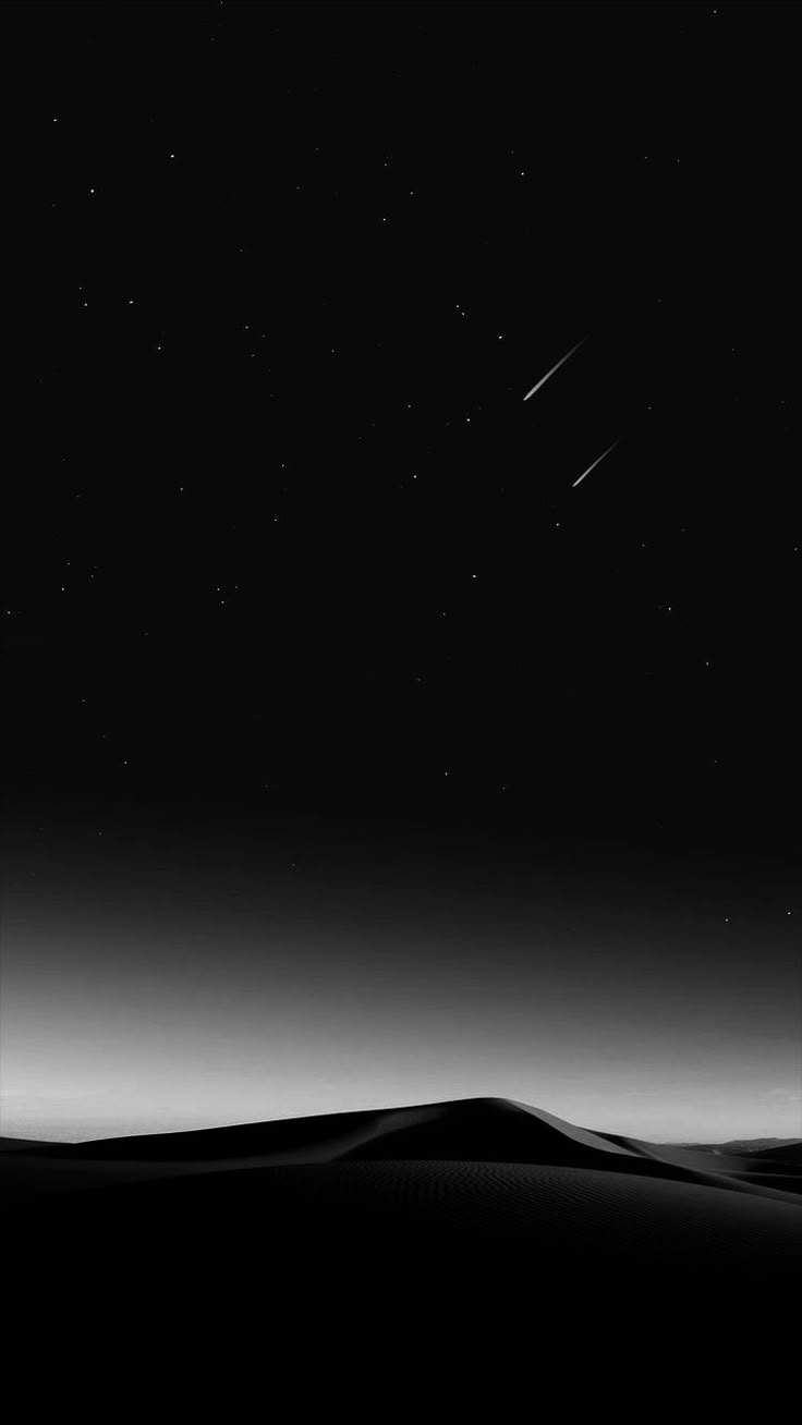 the night sky is black and white, with stars in the distance above sand dunes