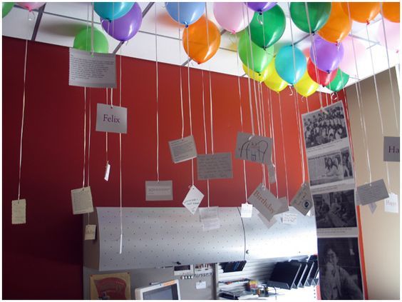 many balloons are hanging from the ceiling with notes attached to them and some pictures hang on the wall