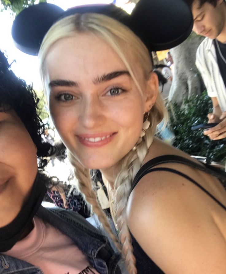 two women are posing for a photo with mickey mouse ears on their heads and braids in front of them