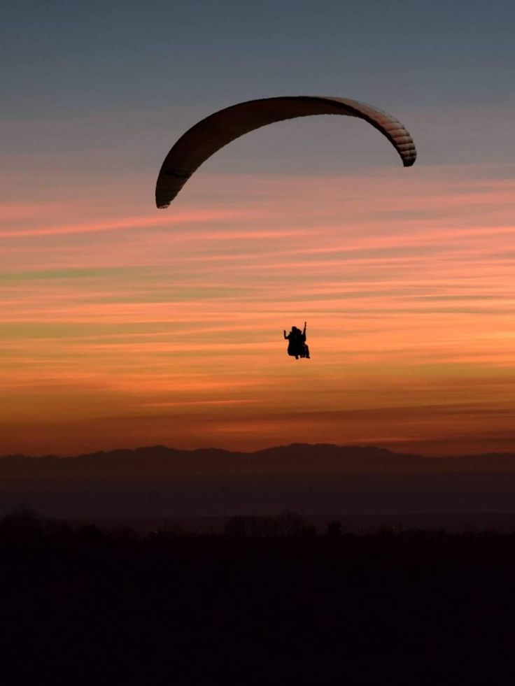 a paraglider is flying in the sky at sunset