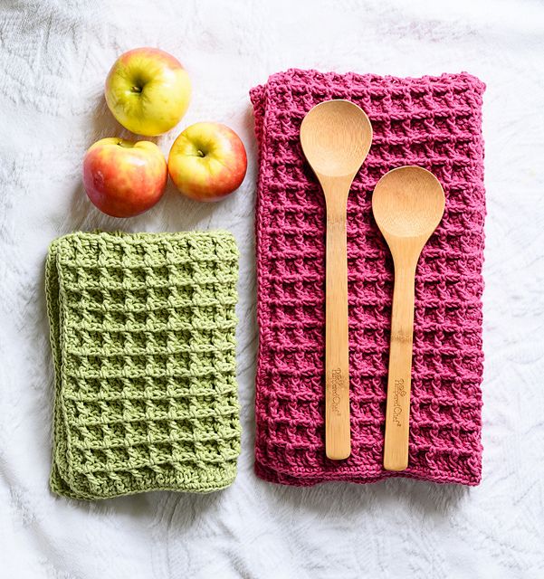 a crocheted dish towel with spoons and an apple on the side next to it