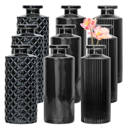 a group of black vases with flowers in them on a white background and one is empty